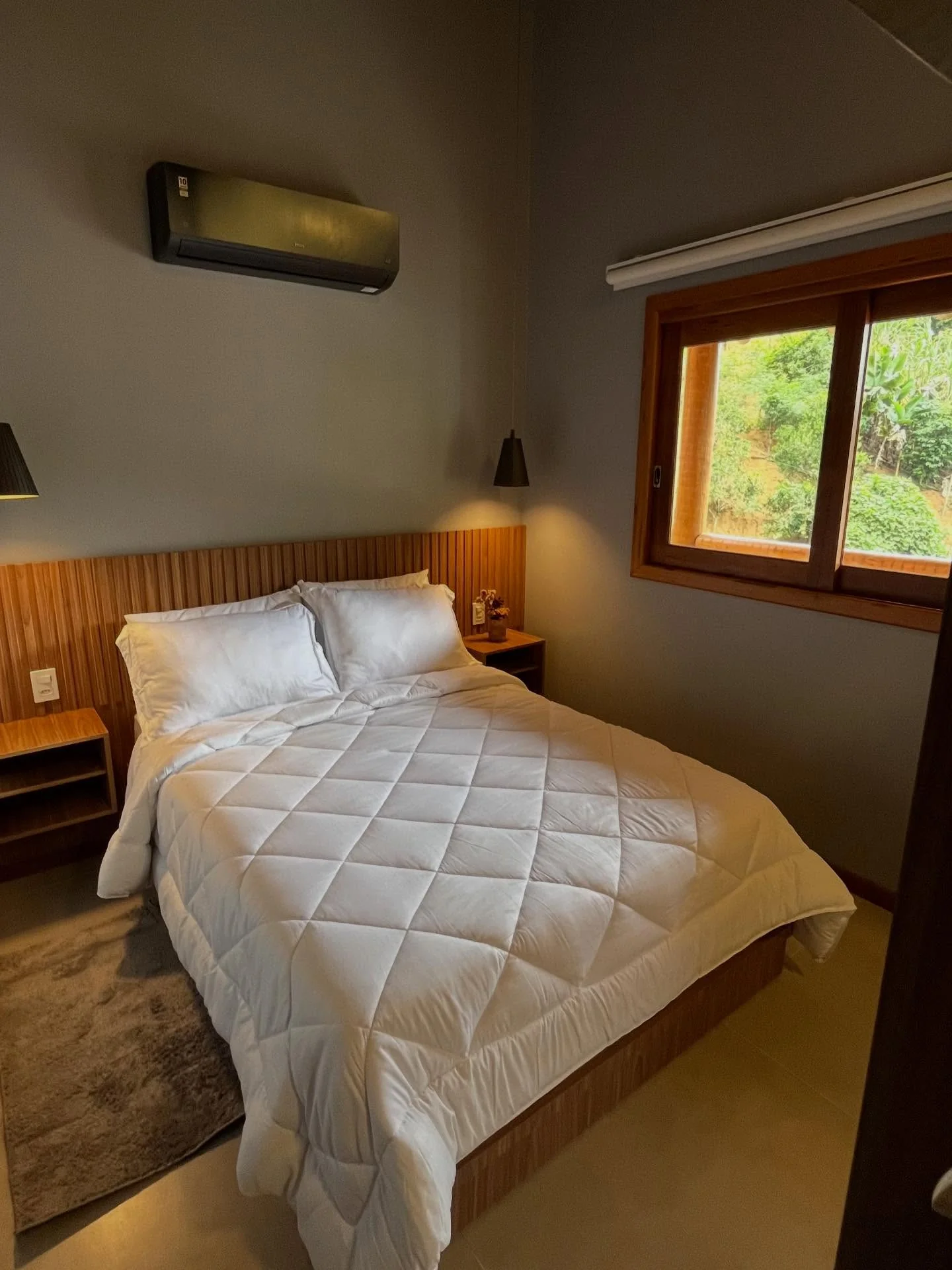 Quarto de um dos chalés do Vila Florença, com teto de madeira, ar-condicionado e cama de casal